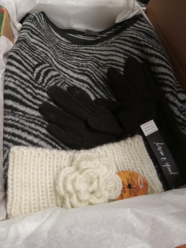picture of boxed gift featuring the poncho plus an ivory colored headwarmer and black gloves.