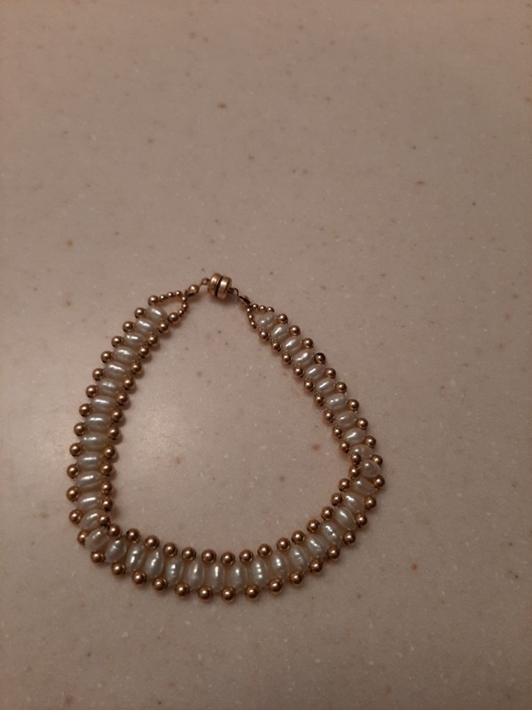 image of bracelet made of white seed pearls woven with gold-filled beads to make a band of pearls with gold-filled beads on top and bottom